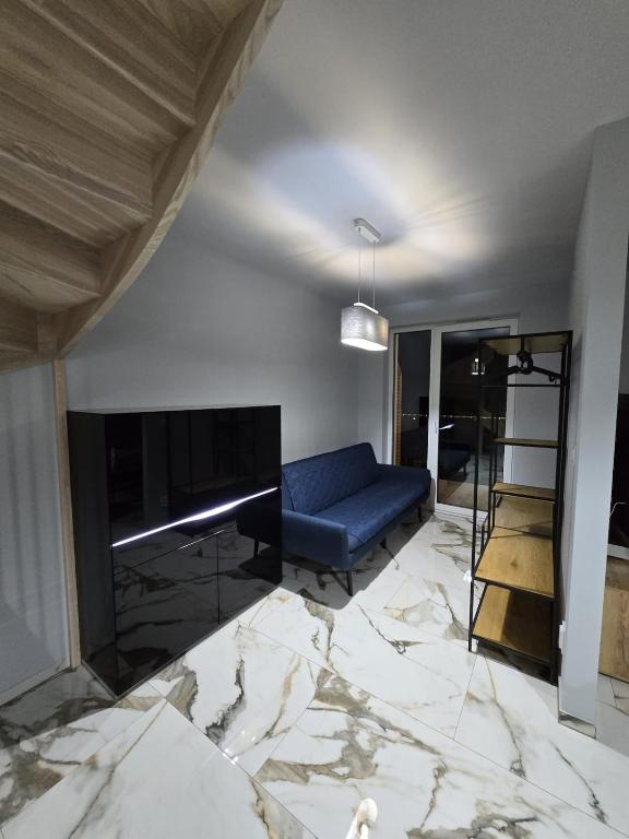 a living room with a blue couch and a fireplace at Apartament Sosnowy Las Widok na morze in Rowy