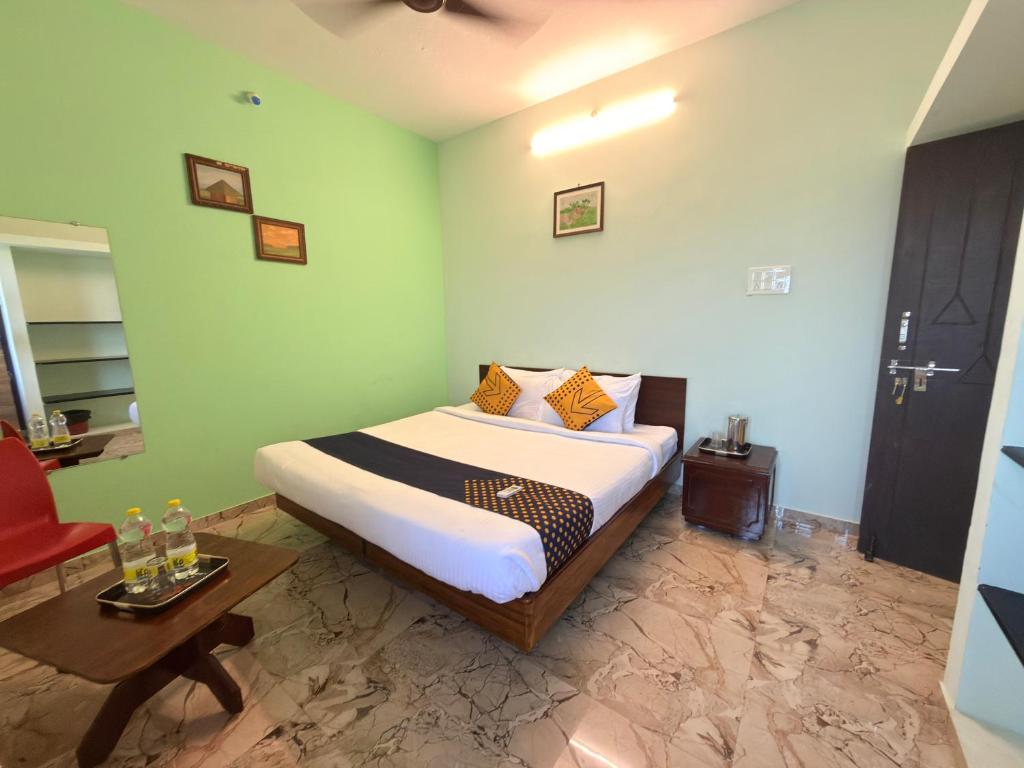 a bedroom with a bed and a table in it at Naadi Grand Inn in Thanjāvūr