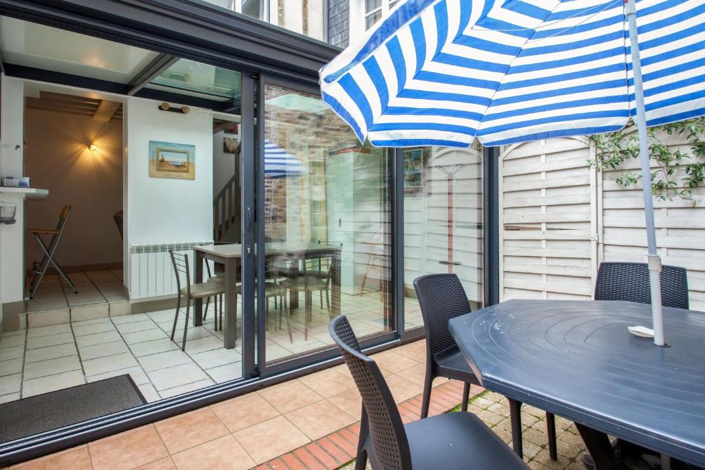 a patio with a table and chairs and an umbrella at Maison charmante près de Sainte Catherine in Honfleur