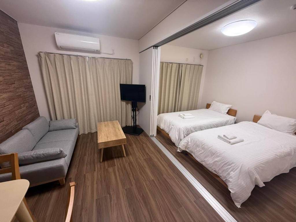 ein Hotelzimmer mit zwei Betten und einer Couch in der Unterkunft casa de sol in Miyakojima