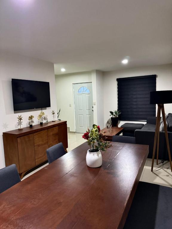 a living room with a wooden table and a tv at Casa en Privada! in Culiacán
