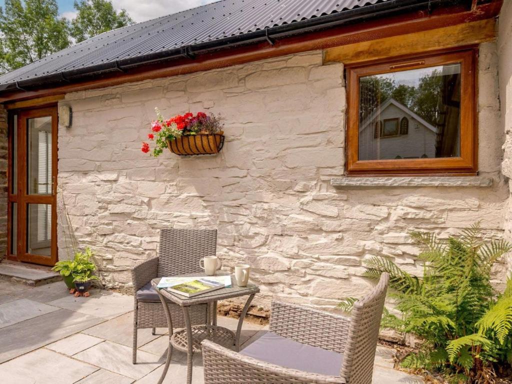 a patio with a table and chairs in front of a stone building at 1 Bed in Clyro oc-86975 in Clyro