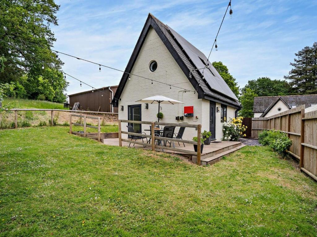 a white barn with a deck and an umbrella at 1 Bed in Pontypool oc-83405 in Mamhilad