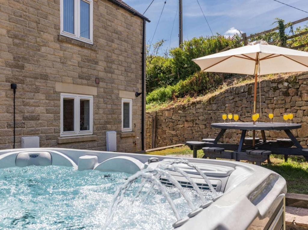 a pool with an umbrella and a table and a table and a picnic table at 5 Bed in Matlock oc-88486 in Crich