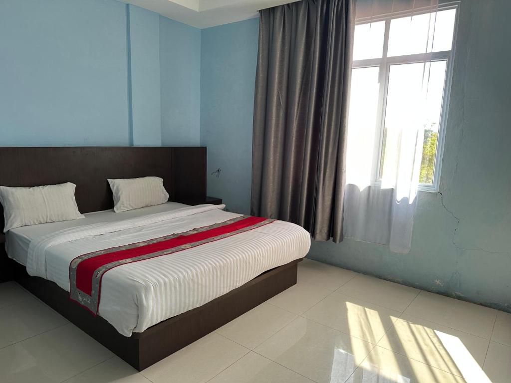 a bedroom with a large bed with a large window at Hotel Melayu Bedendang in Tanjunguban