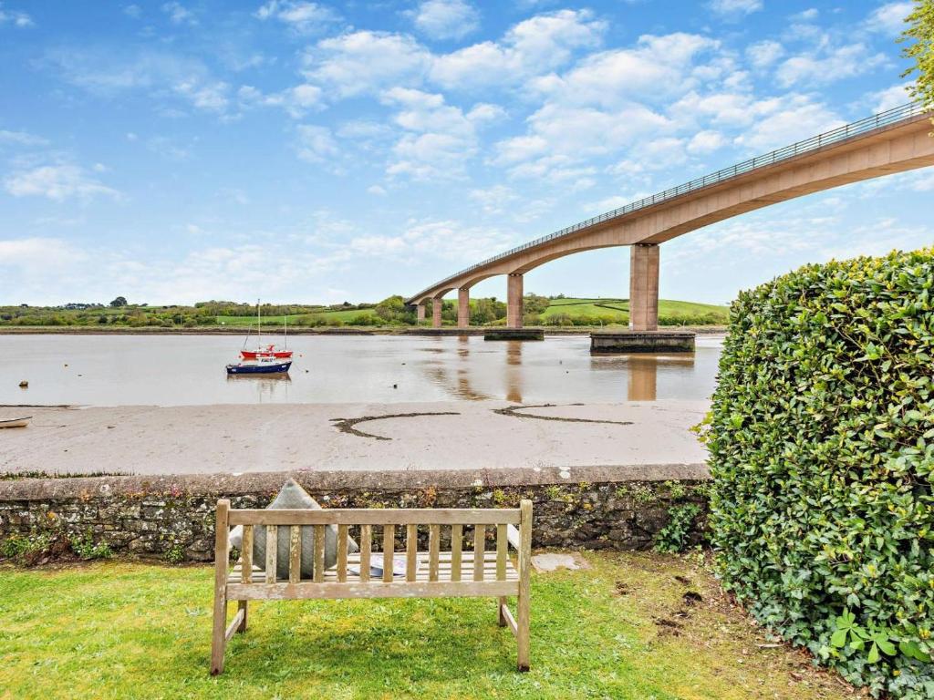 a wooden bench sitting next to a river with a bridge at 2 Bed in Bideford oc-40281 in Northam