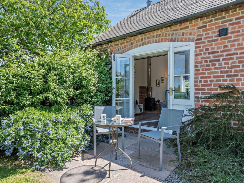 a patio with two chairs and a table in front of a brick house at 1 Bed in Craven Arms oc-54926 in Clungunford
