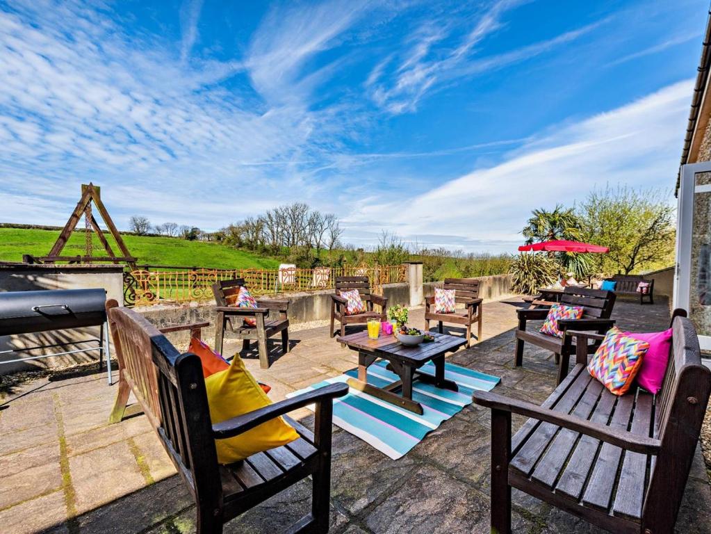 a patio with wooden benches and tables and a grill at 6 Bed in Bideford oc-thorn in Buckland Brewer