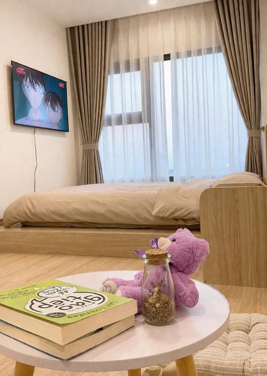 a purple teddy bear sitting on a table with a book at Homestay Nhà Thu Thu Vinhome Ocean Park in Gia Lâm Pho