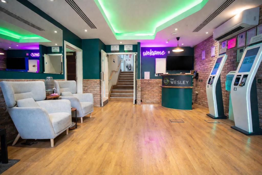 a lobby with a waiting room with a tv and chairs at The Wesley Euston in London