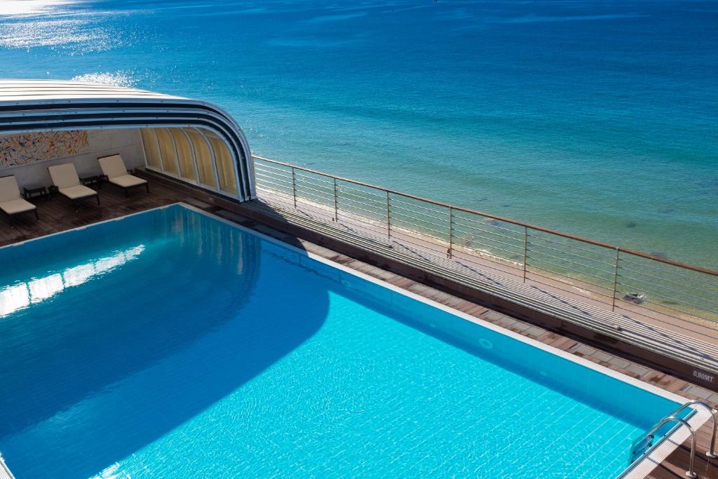 a swimming pool with the ocean in the background at SANA Sesimbra Hotel in Sesimbra