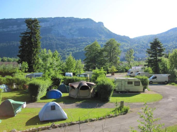 a group of tents in a field with mountains in the background at Camping Le SIGNAL Nantua in Nantua