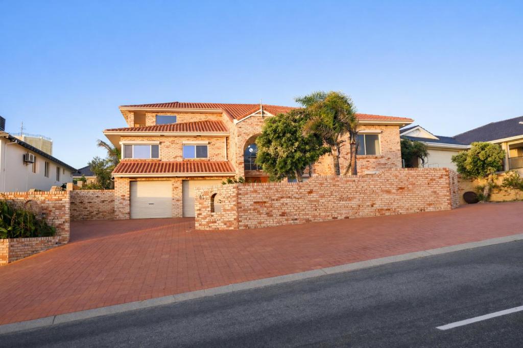 a house with a brick wall next to a street at Infinity Views in Utakarra