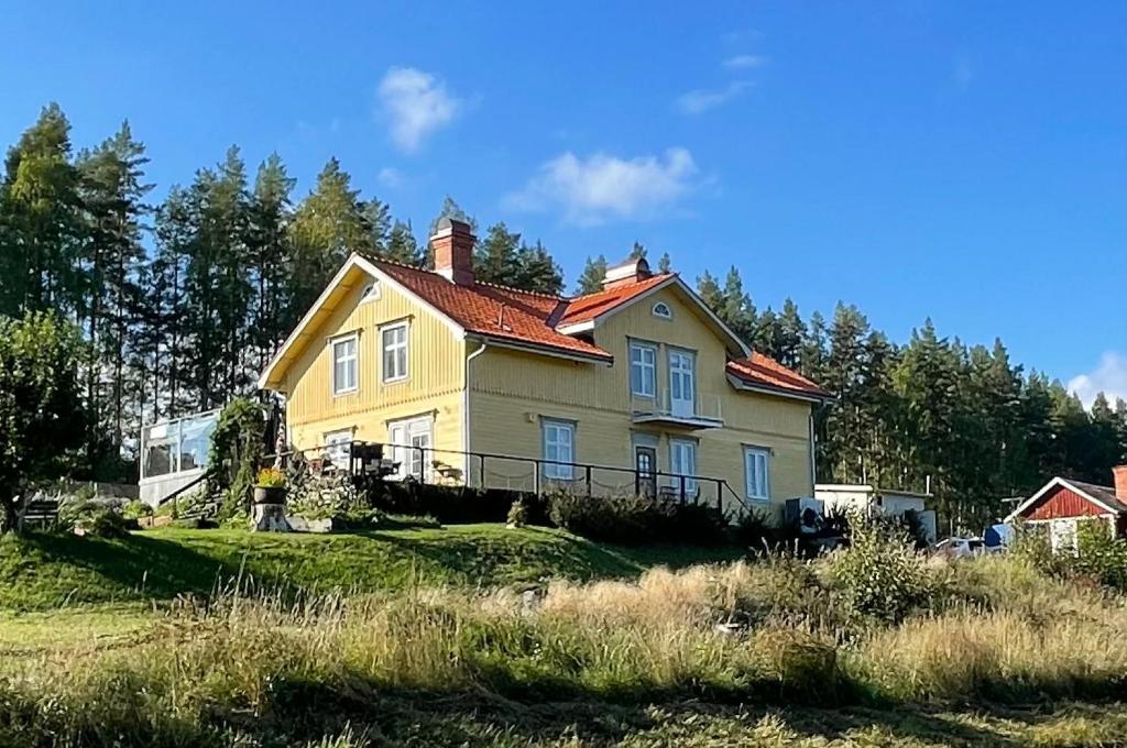 a yellow house with a red roof on a field at Granbo station in Granbo