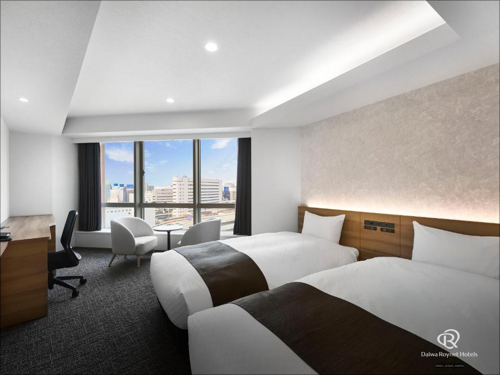 a hotel room with two beds and a desk at Daiwa Roynet Hotel Nagoya Eki Mae in Nagoya