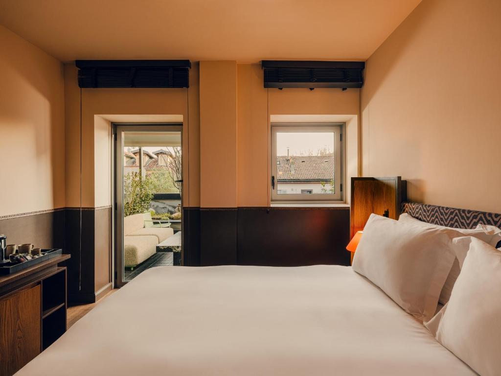 a bedroom with a large bed and two windows at Aethos Hotel Milan in Milan