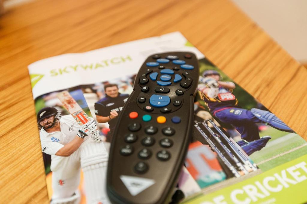 a remote control sitting on top of a baseball book at Fitzherbert Castle Motel in Palmerston North
