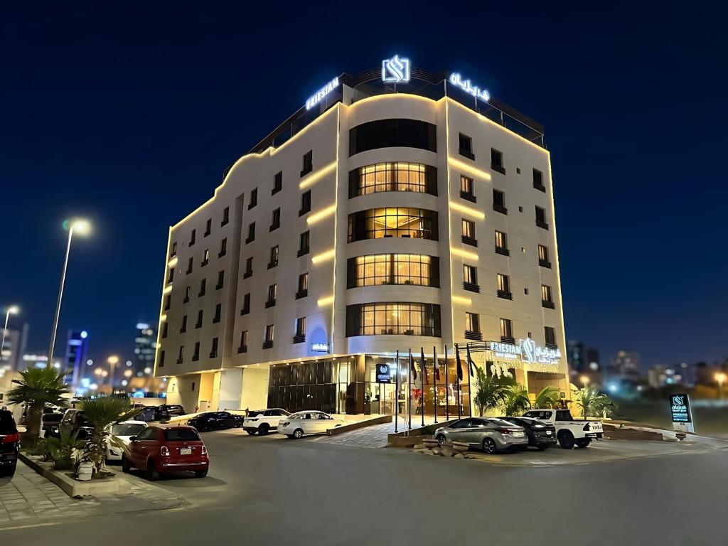 a hotel building with cars parked in a parking lot at Friesian Hotel Apartments in Jeddah