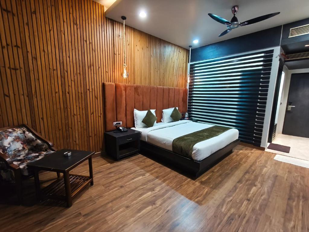 a bedroom with a bed and a chair in it at Hotel Tushar Elegant in Ghaziabad