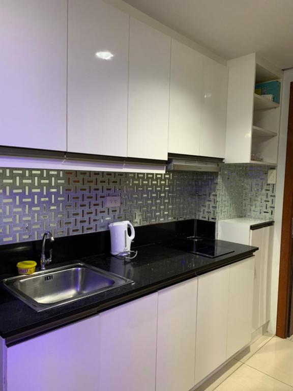 a kitchen with white cabinets and a sink at MOA Prime Staycation Sea Residences in Manila