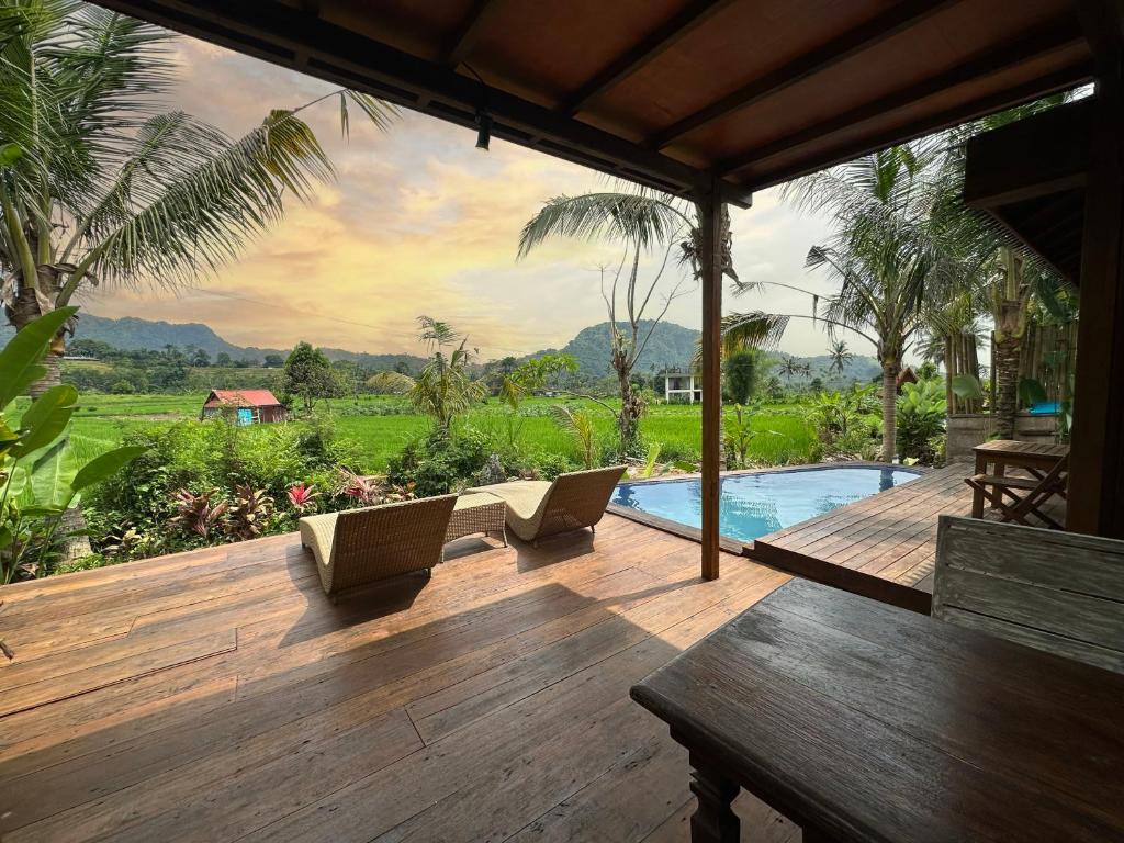 a wooden deck with two chairs and a swimming pool at Kelapa Sunrise Villa in Silebeng