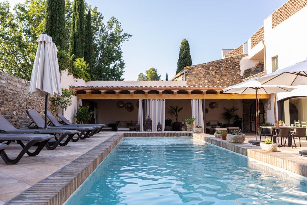 an outdoor swimming pool with chairs and an umbrella at Hotel Boutique Monells Summum in Monells
