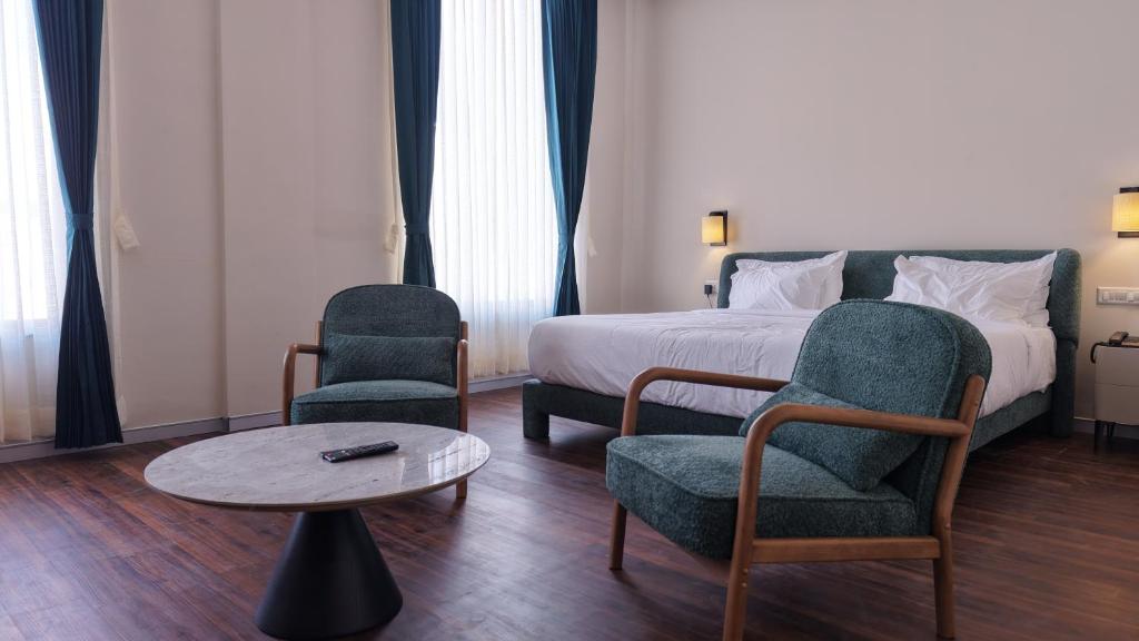 a hotel room with a bed and two chairs and a table at Aanya Taara Resort- Mettupalayam in Mettuppālaiyam
