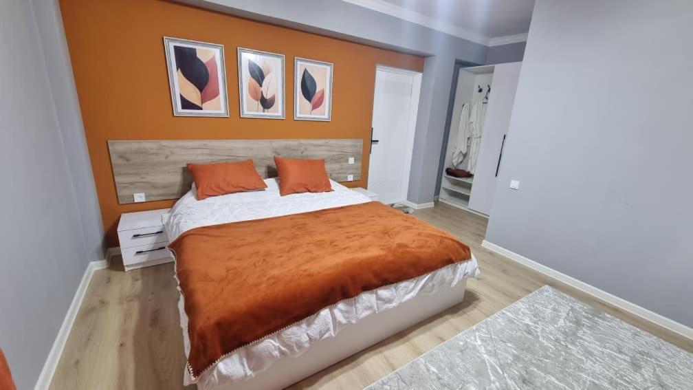 a bedroom with a large bed with an orange blanket at Orom Hotel in Dushanbe