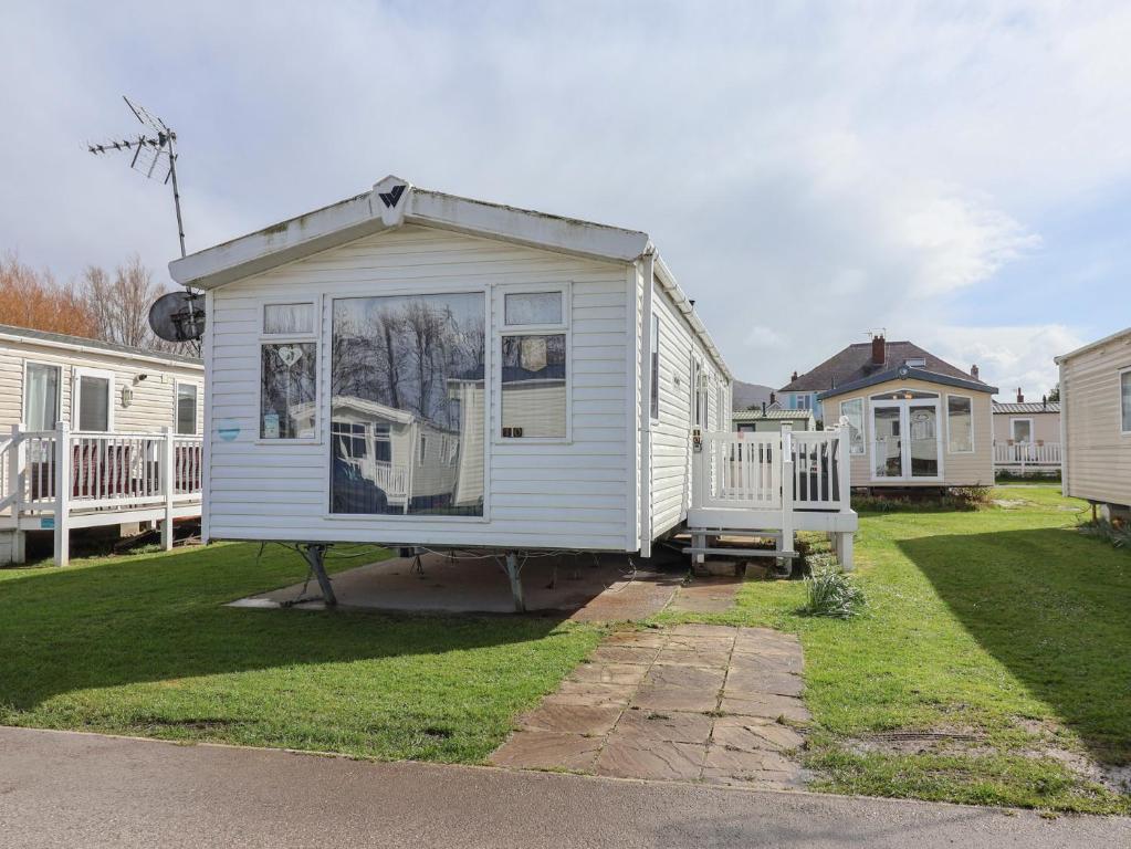 a small white house with a window in a yard at Caravan CP10 in Prestatyn