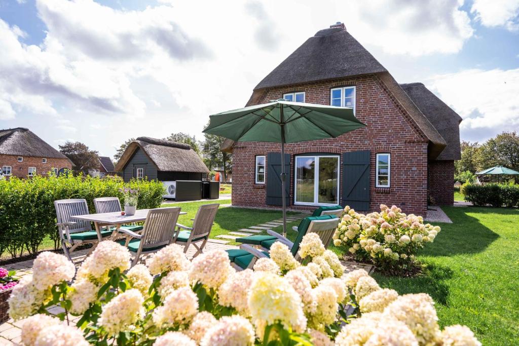 a garden with a table and chairs and an umbrella at Haus an der Koppel in Borgsum