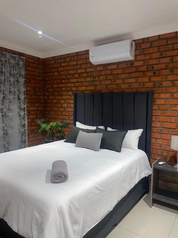 a bedroom with a large white bed with a brick wall at Kubbe Comfort Corner in Bloemfontein