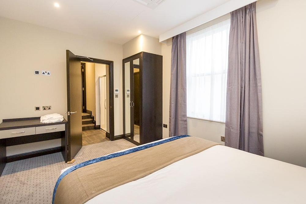a bedroom with a bed and a desk and a window at The Westbourne Residences in London