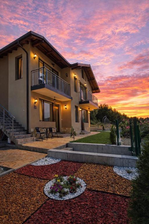 a house with a sunset in the background at Къща за гости "СЛАВЕНА" in Dospat