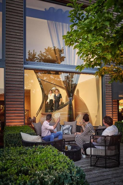 Eine Gruppe von Menschen sitzt auf einem Sofa vor einem Gebäude in der Unterkunft Bad Bubendorf Design & Lifestyle Hotel in Bubendorf