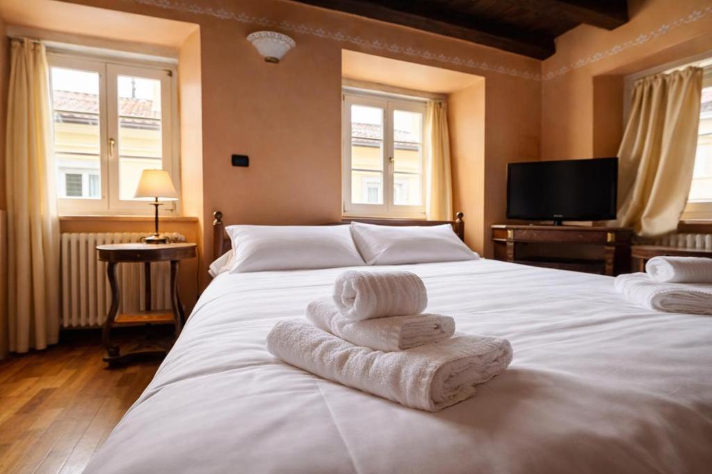 a bedroom with a large white bed with towels on it at Hotel Portacavana in Trieste