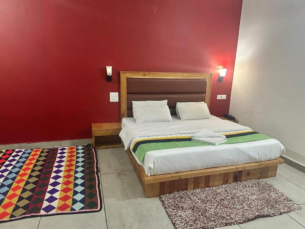 a bedroom with a large bed and a red wall at Woodward 2 by 4 Wildflower in Kasol