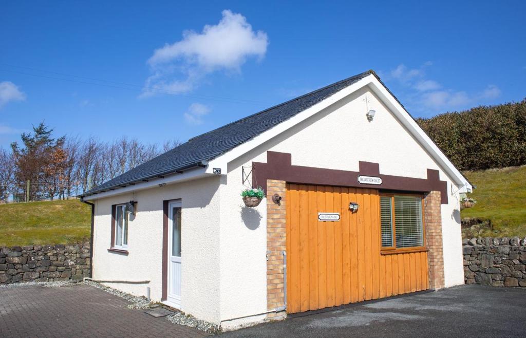 a small white building with a wooden door at Skeabost View Chalet in Portree