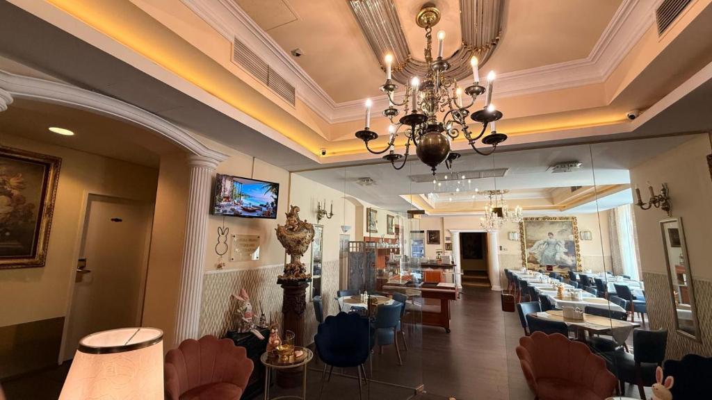 a restaurant with a chandelier and tables and chairs at Hotel Pension Excellence in Vienna
