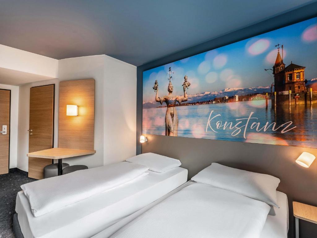 a bedroom with two beds and a large painting on the wall at B&B Hotel Konstanz in Konstanz