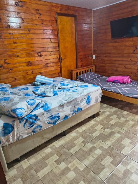two beds in a room with wooden walls at Pousada da Nani in São Gabriel