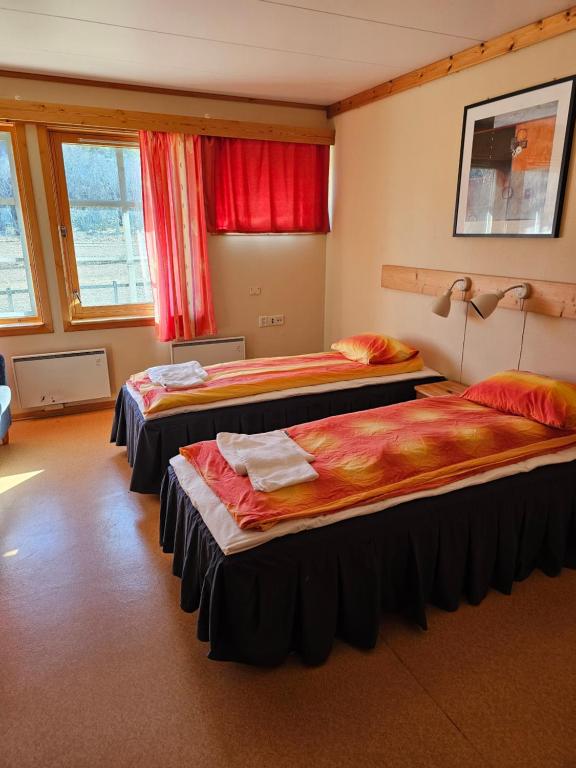 two beds in a room with red curtains at Vertshuset gamlebirkeli in Drilen