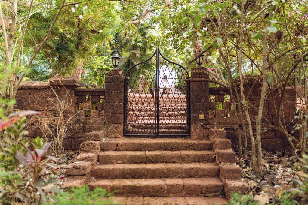 a gate to a garden with stairs and trees at Botanique Goa in Assagao