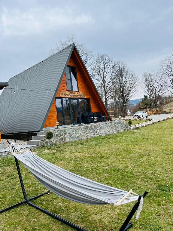 a hammock in a field in front of a house at Cabana Muncelus in Lupşa