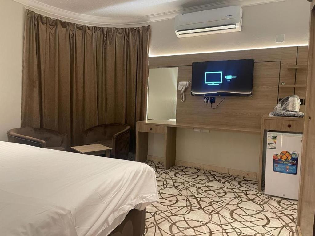 a hotel room with a bed and a desk with a television at Dvina Hotel دفينا in Tabuk