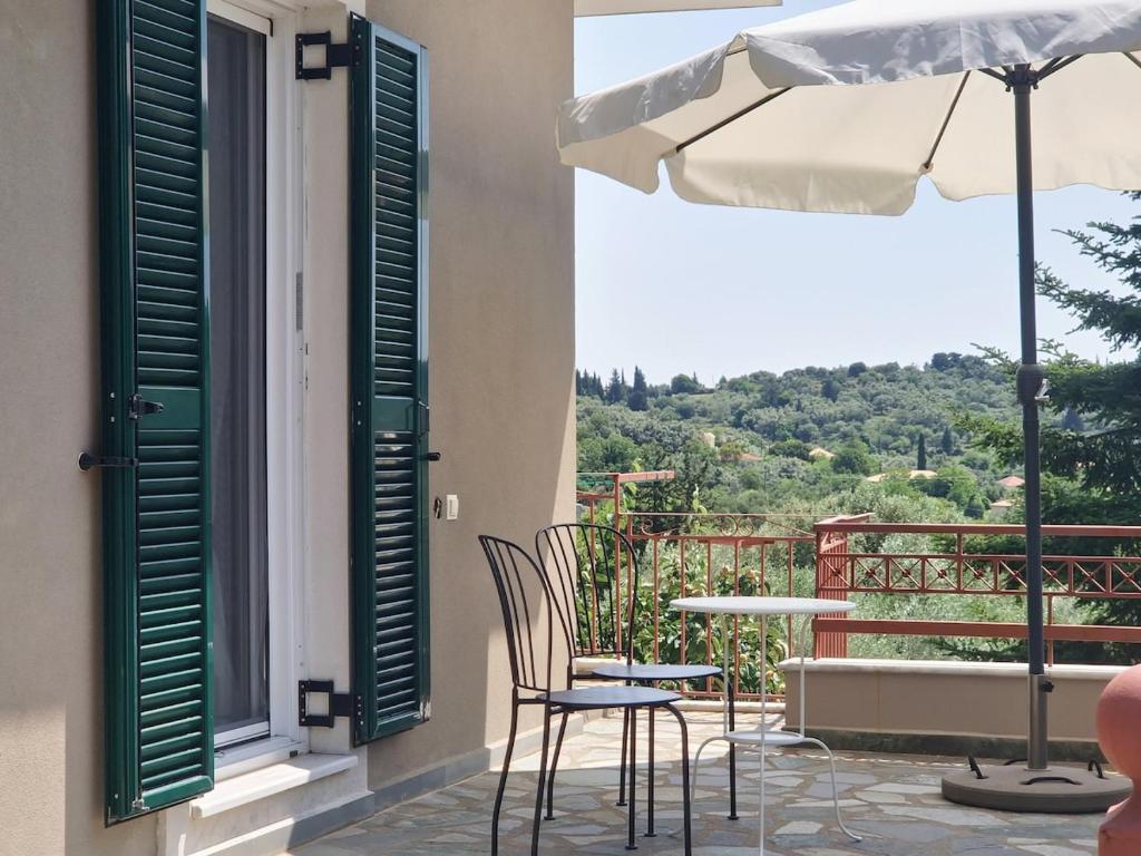 a patio with a table and chairs and an umbrella at Peonia Flower House in Asprogerakata