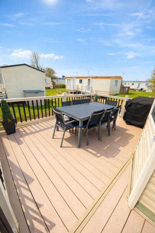 a patio with a table and chairs on a deck at Long Beach Park Caravan, Hembsy in Great Yarmouth