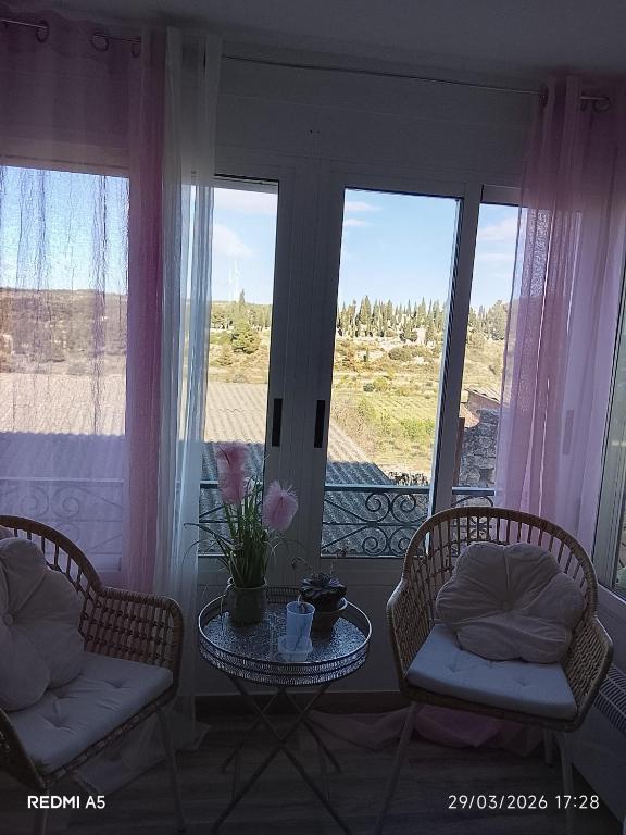 a living room with two chairs and a table and windows at Ca la Carme in Villalba dels Arcs