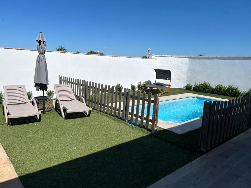 a fence with two chairs and a swimming pool at Casa El Viaje in El Palmar