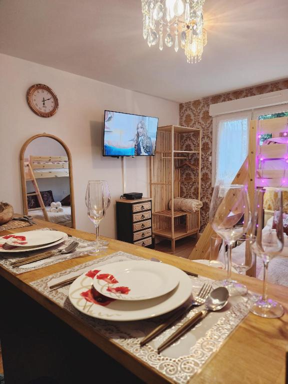 a dining room with a table with plates and wine glasses at Luxy Room in Courseulles-sur-Mer