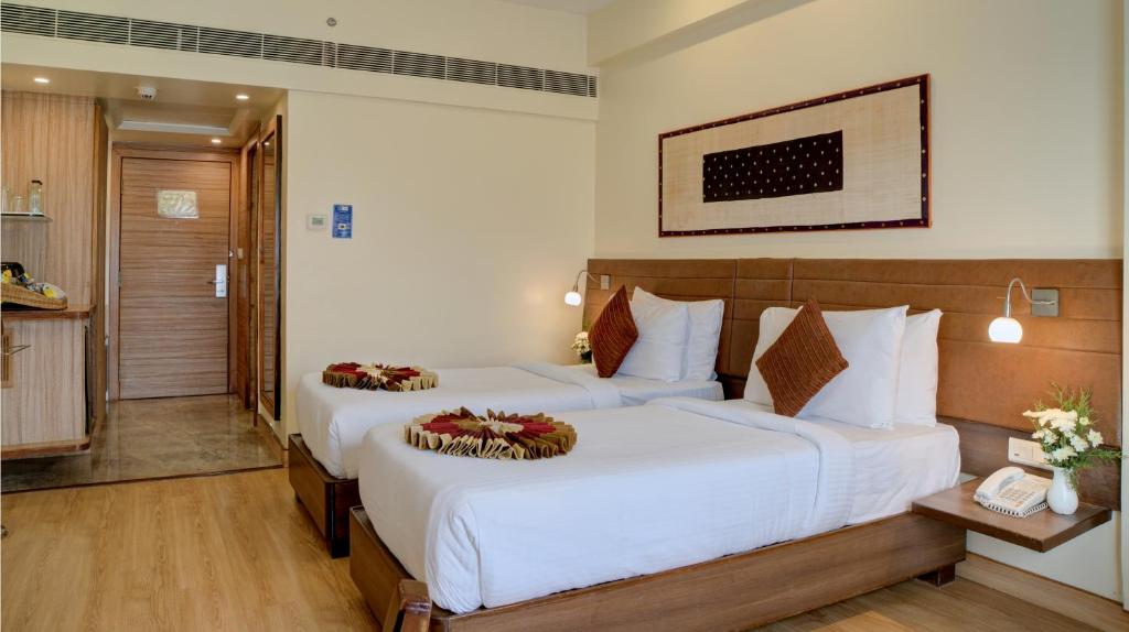 a hotel room with two beds and a bathroom at Hotel Tamilnadu Pandiyan Madurai in Madurai
